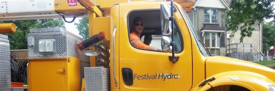 a festval hydro lineworker sits in the passenger seat of a yellow festival hydro bucket truck.