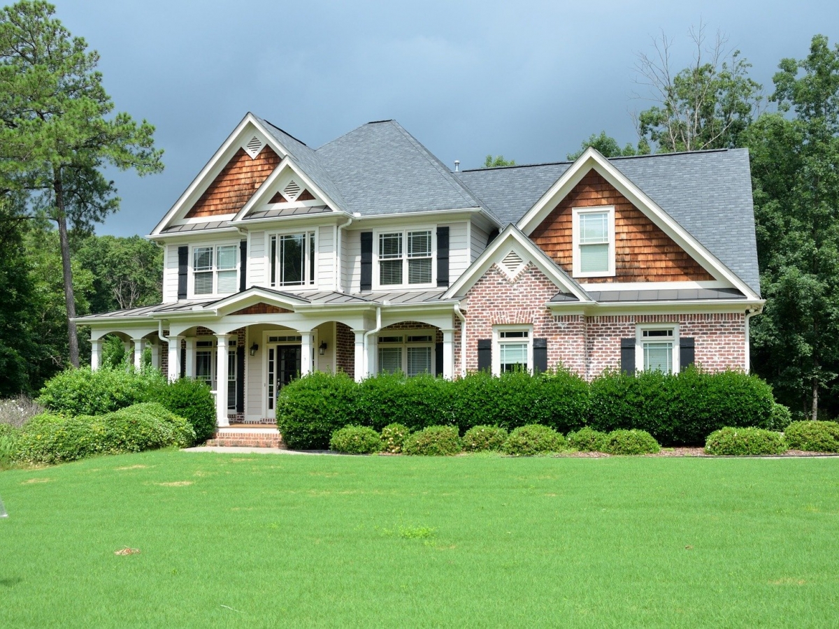 a large house with a gray roof stands among large hedges with a large frontage.