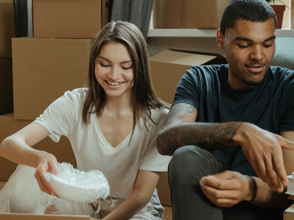 A man and woman are unpacking brown cardboard moving boxes.